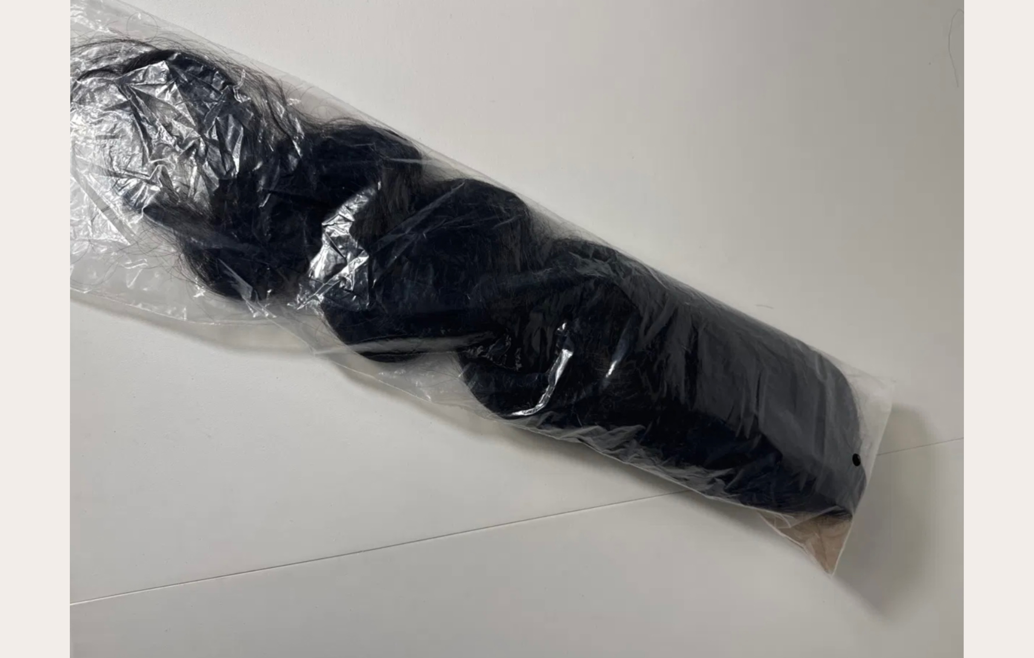 Body wave wig rolled and compressed inside a clear plastic bag — wave pattern distorted from transit pressure
